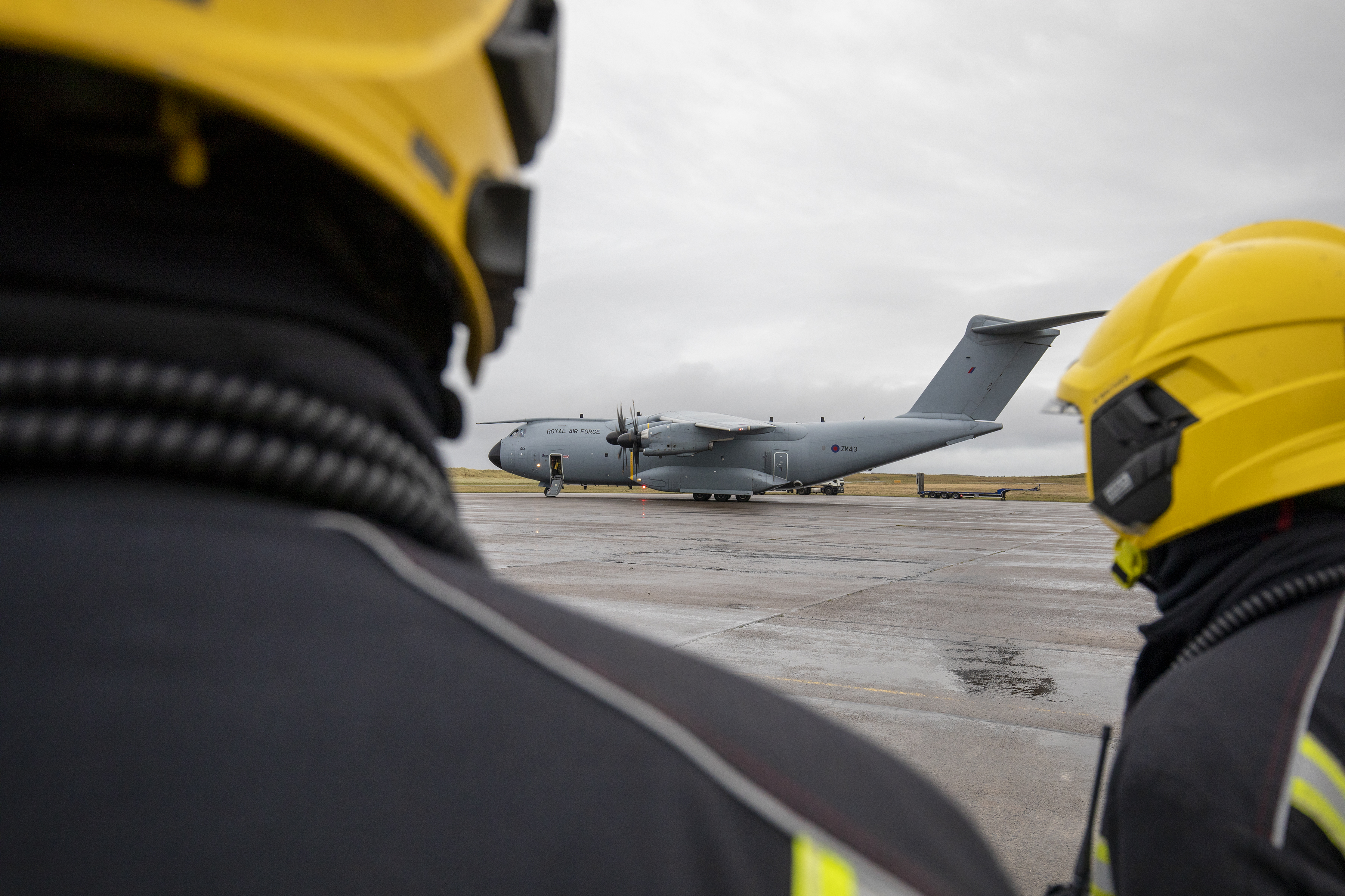 Personnel wear specialist head gear and look toward Atlas A400 on the runway.